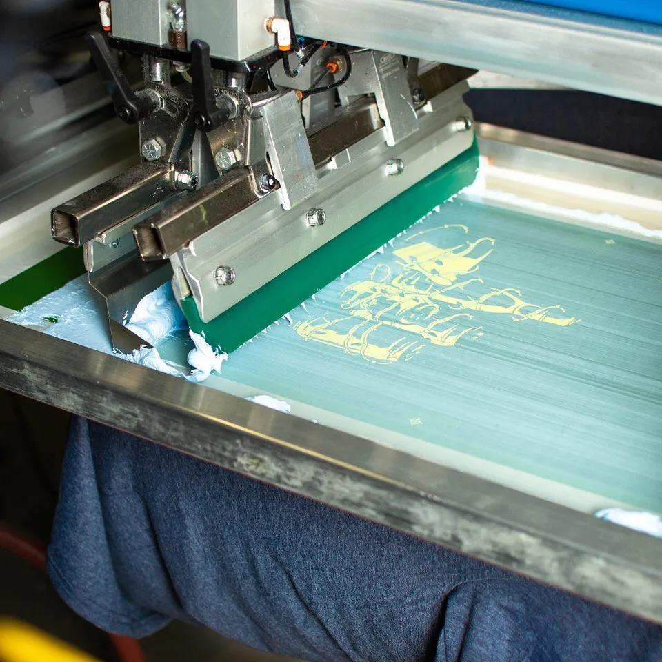 Printing team preparing ocean-inspired T-shirt design in studio – hands-on process, fabric, and heat press visible.